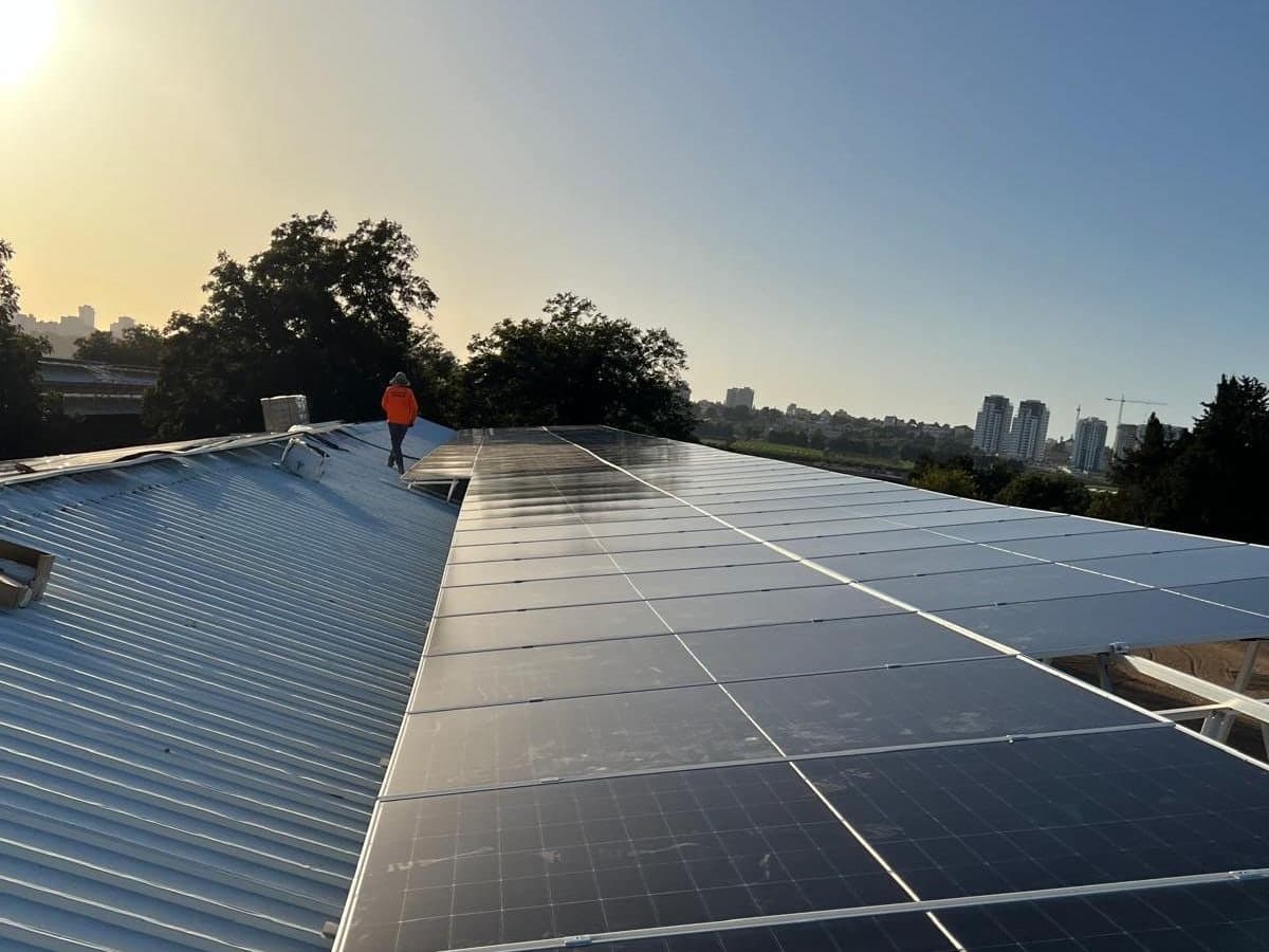 איש צוות של OA Solar על רכס גג במהלך התקנה, בשעת השקיעה