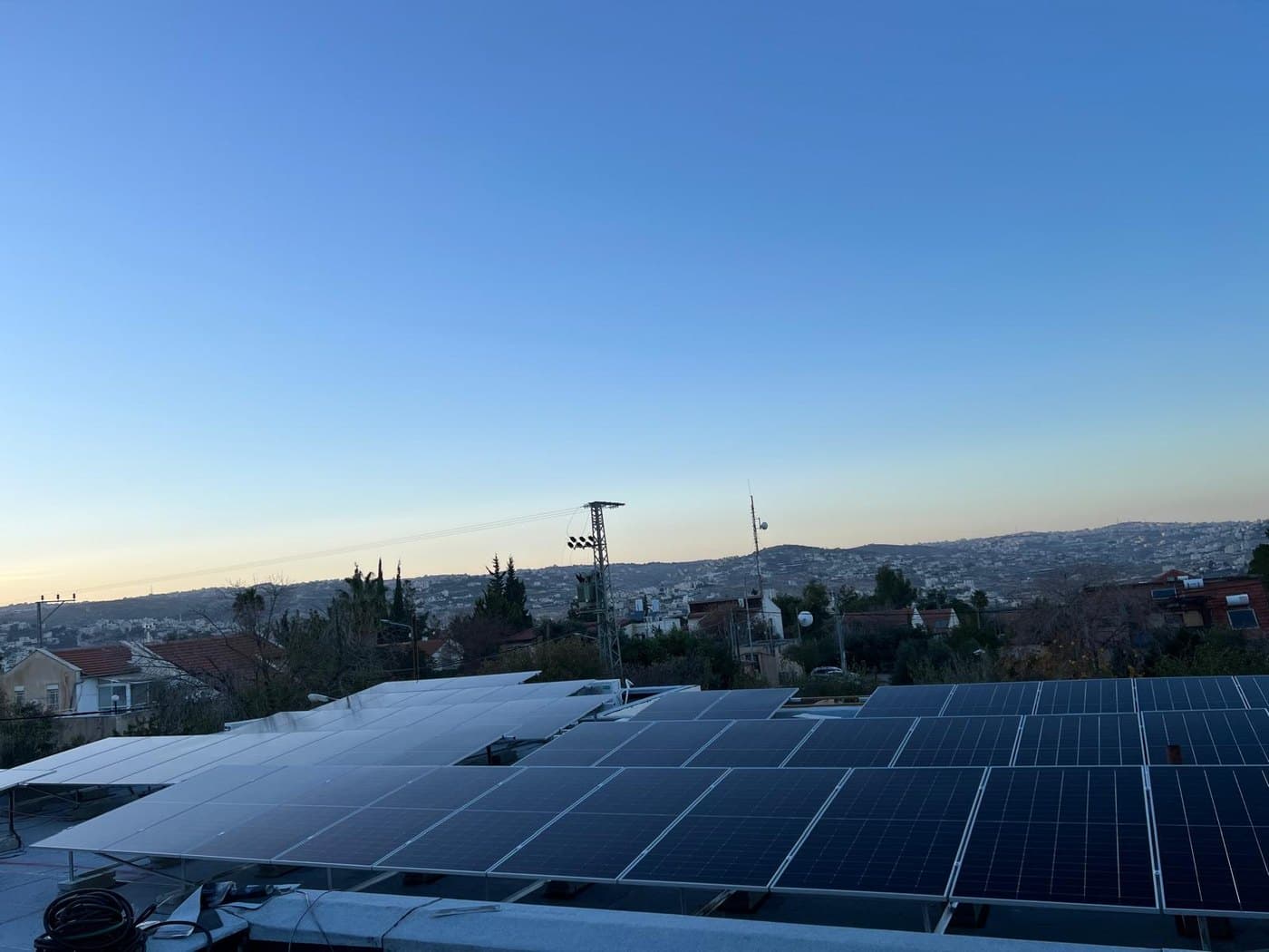 מערכת סולארית על גג המשקיף על עיר בשעת בין הערביים